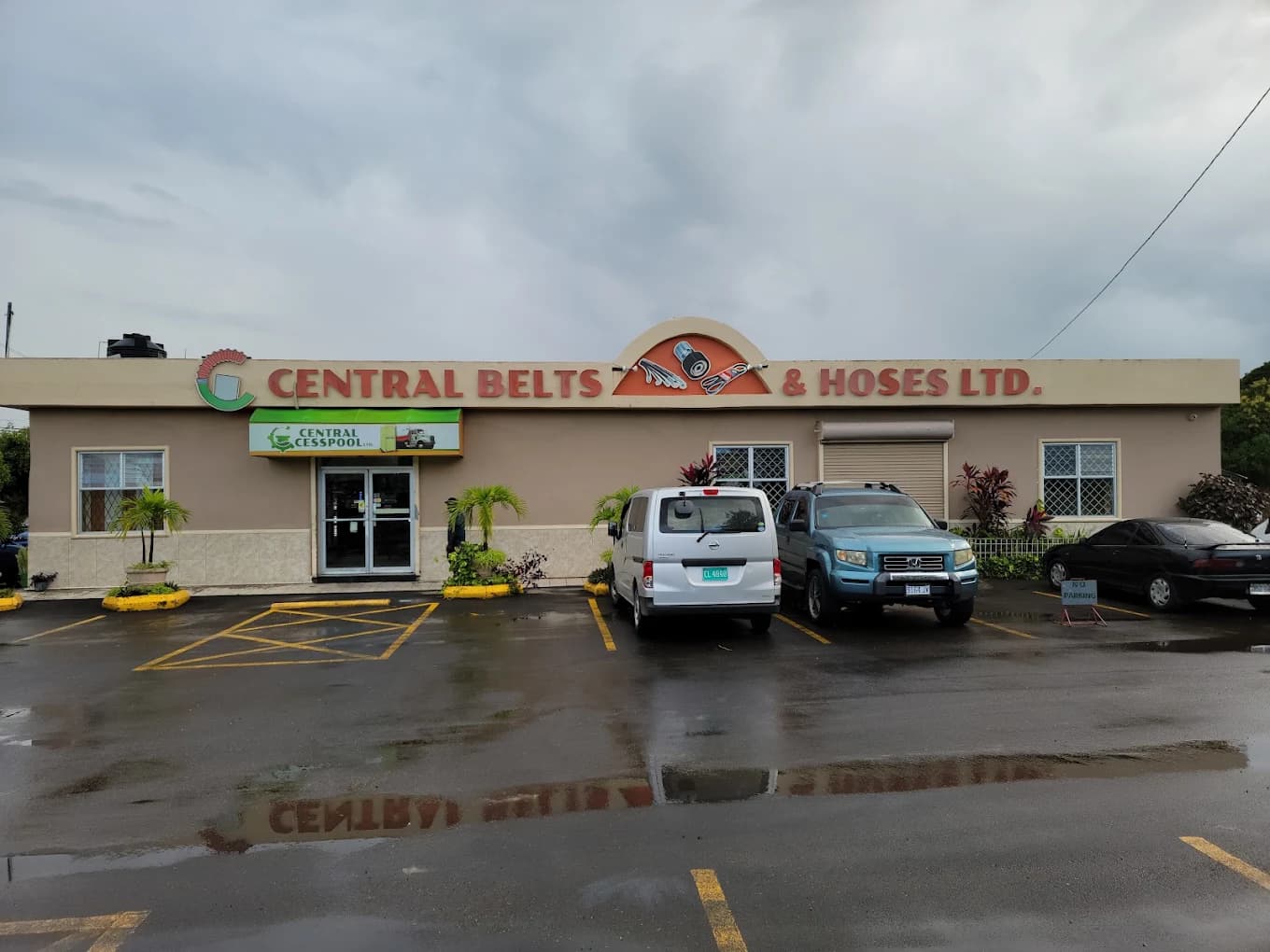 Central Belts & Hoses Ltd. storefront with cars parked on a wet asphalt lot.